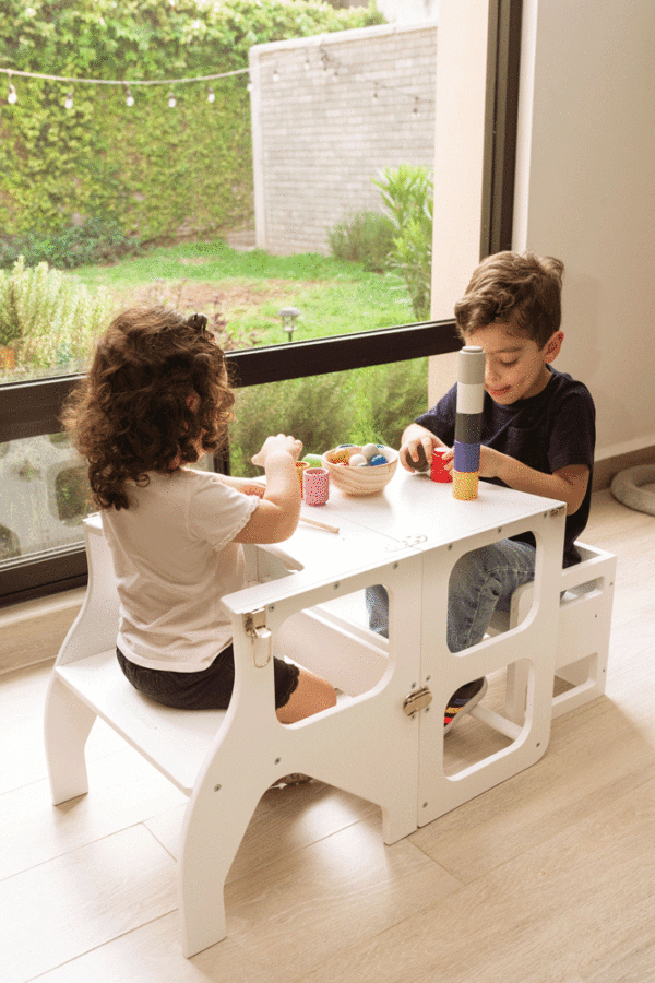 Niños en mesa montessori, torre de aprendizaje convertible